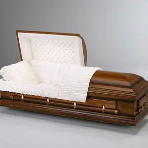 A wooden casket with a partially open lid, displaying a white cushioned interior, a matching pillow, and gold-colored handles, set against a plain light gray background.